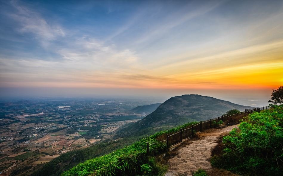 Person sitting on a mountain overlooking misty forested valley